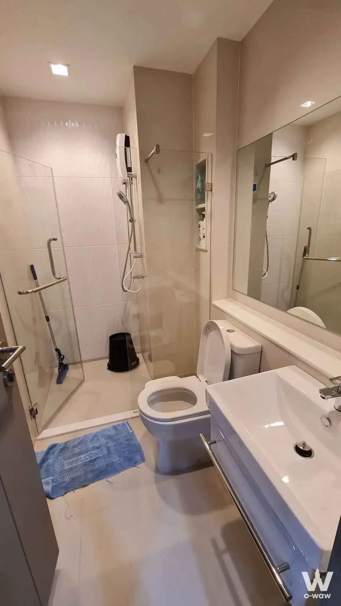 Modern bathroom in Life Asoke condo featuring glass shower, vessel sink, and glossy white tiles