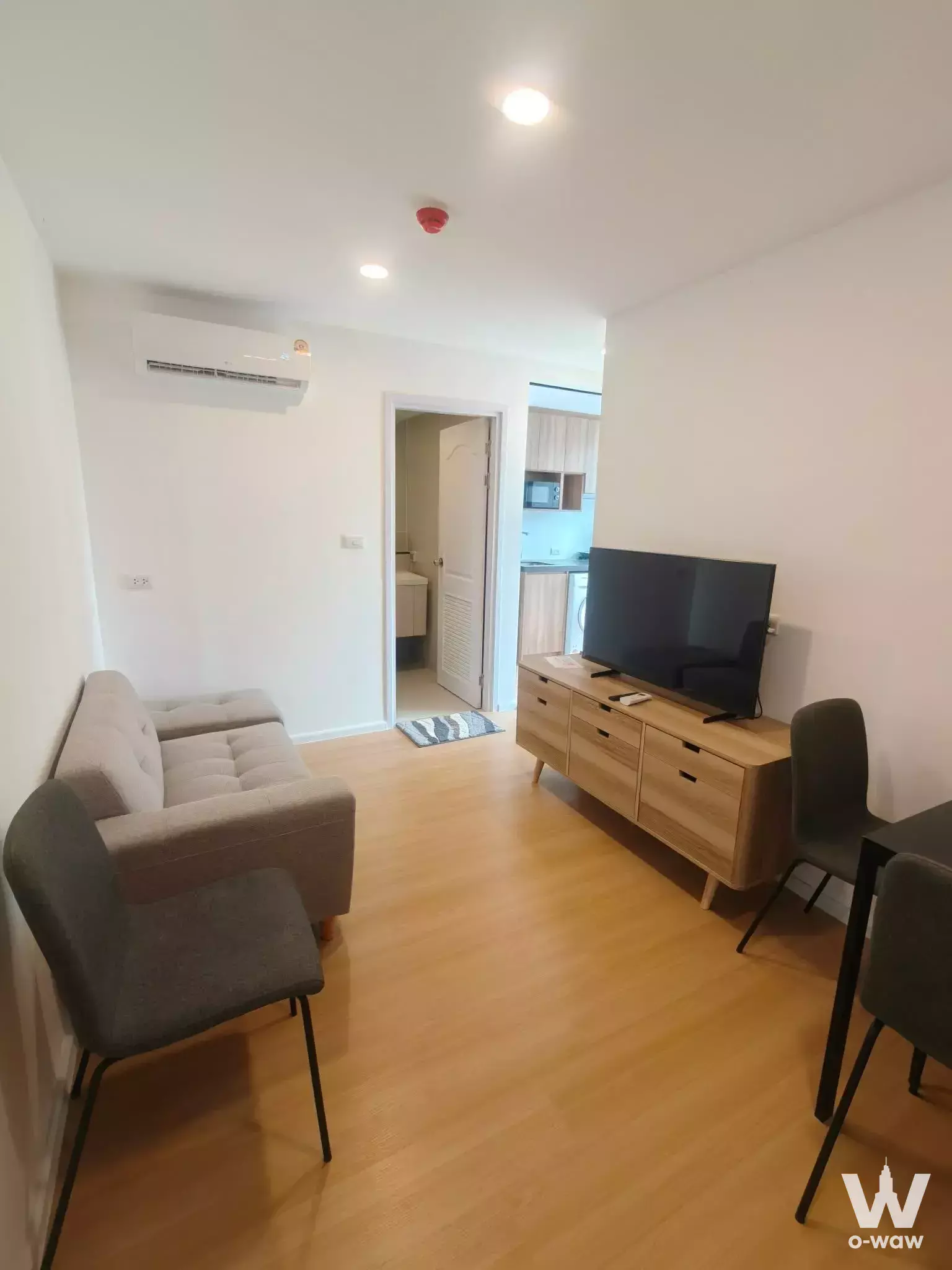 Compact living space in Cerocco Bangna 36 condo with beige sofa oak TV console and open layout