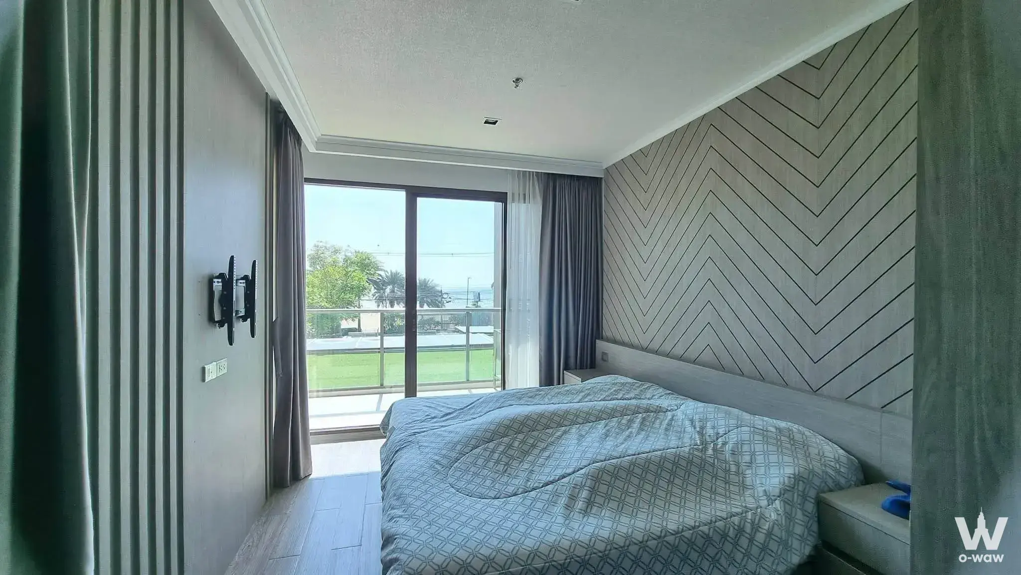 Master bedroom with chevron wallpaper and balcony view at AERAS Beachfront Condominium Jomtien Pattaya