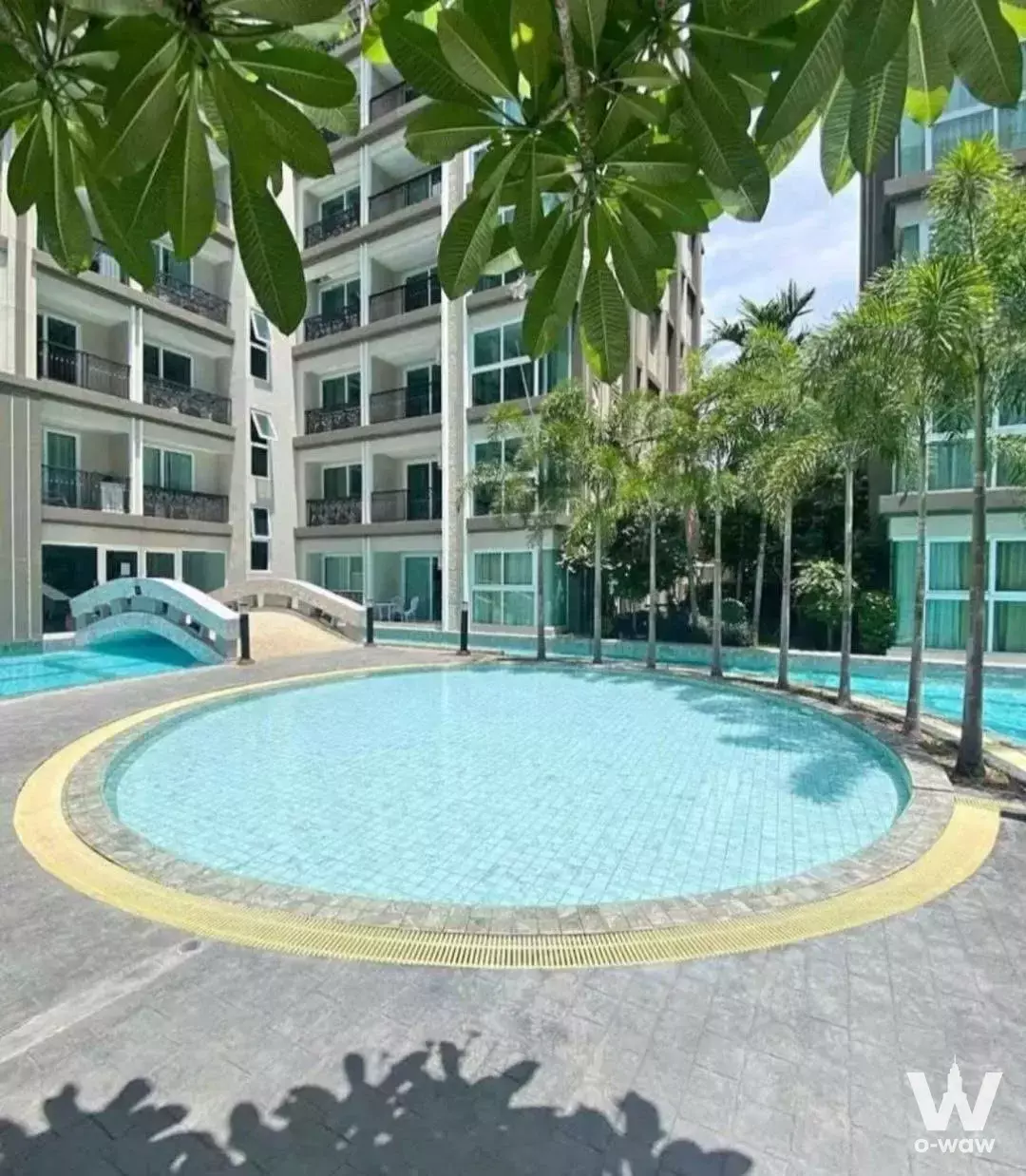 Circular pool with footbridge and palm trees in this 1-bed condo for sale at Dusit Grand Park