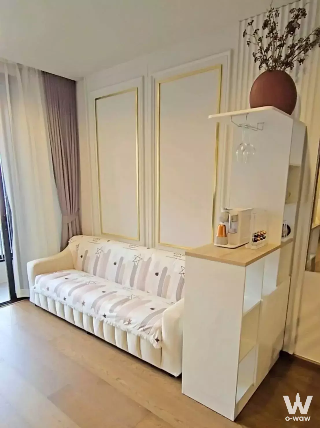 Living room in an Ideo Q Sukhumvit 36 condo featuring cream sofa and open shelving with wine rack
