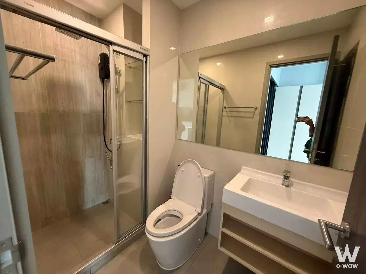 Modern bathroom in The Rich Rama 9 condo featuring glass shower enclosure and floating wood vanity