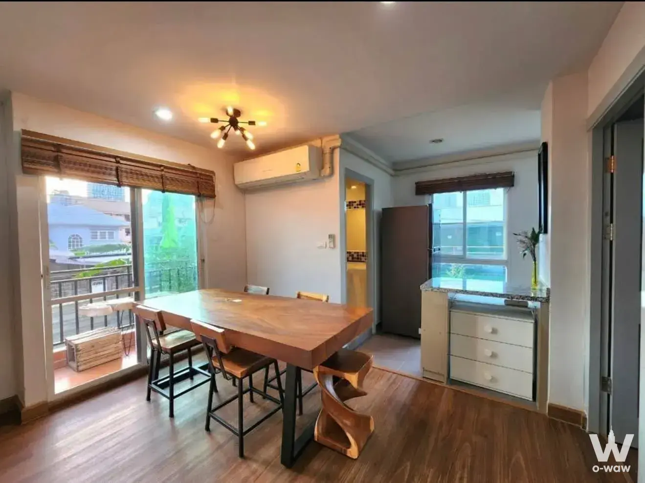 Open-plan dining area in this Regent Home 22 rental features a solid wood table and bamboo balcony shades