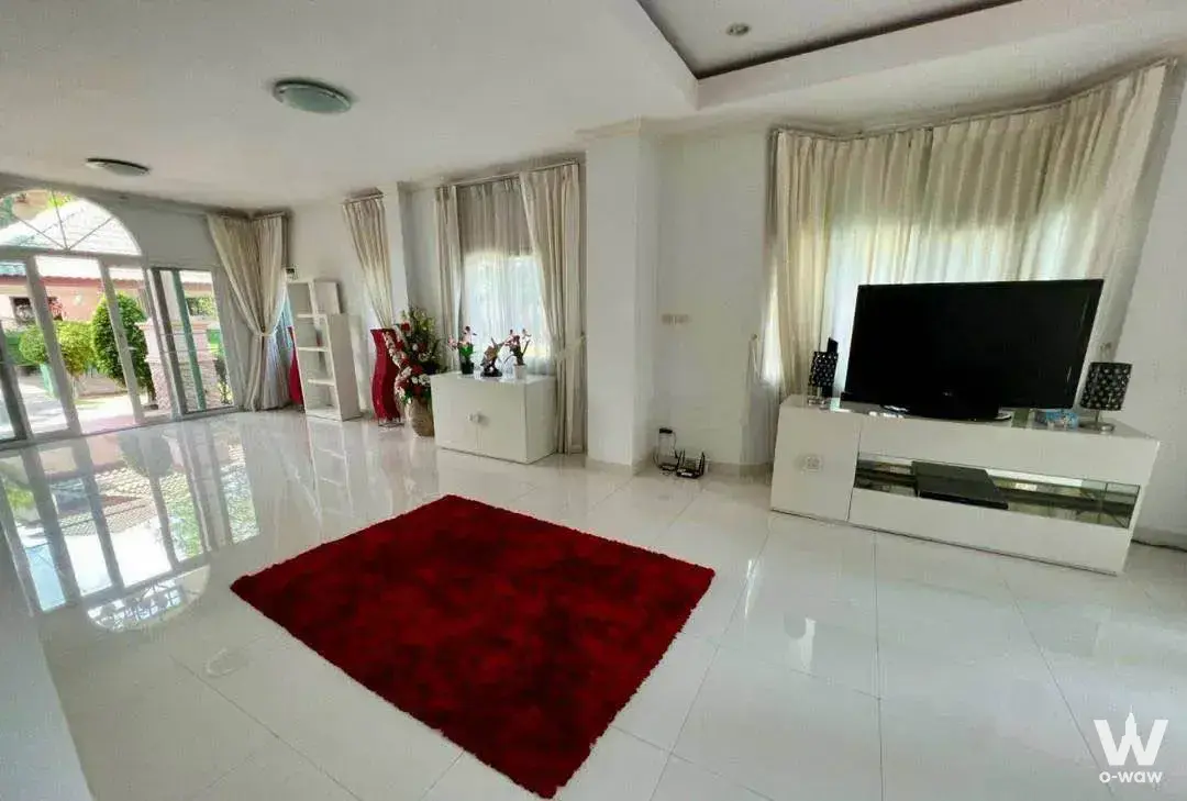 Spacious white living room with red rug, TV console, and sliding doors to patio at Baan Dusit Pattaya View