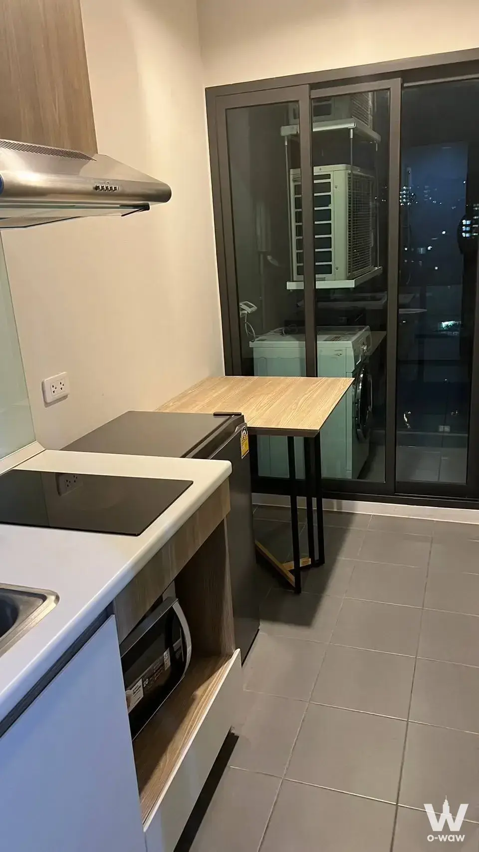 Kitchenette with induction cooktop, microwave, and dining table in an Excel Hideaway Sukhumvit 50 unit