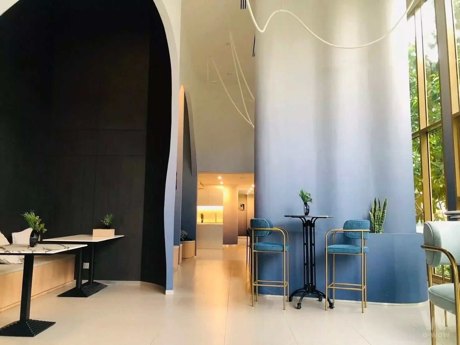 Luxury lobby lounge in Atmoz Tropicana Bangna with vaulted ceilings, blue velvet stools, and floor-to-ceiling glass