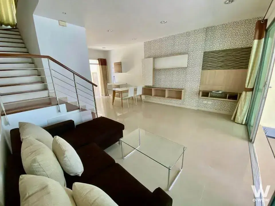 Open-plan living area with sectional sofa and staircase in Baan Klang Muang Urbanion townhouse