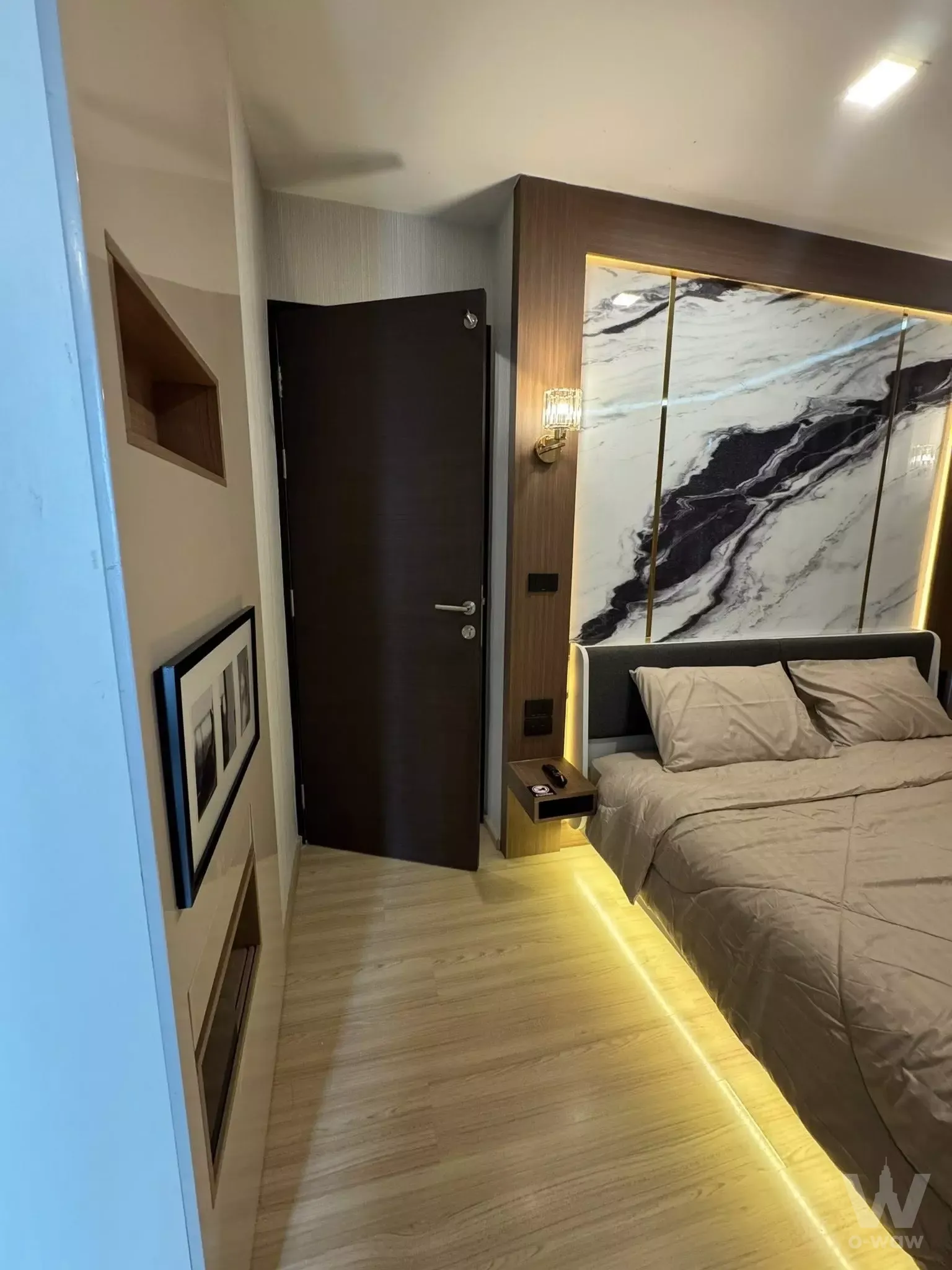 Bedroom with backlit marble headboard wall and warm LED lighting in this RHYTHM Sathorn 1-bed condo