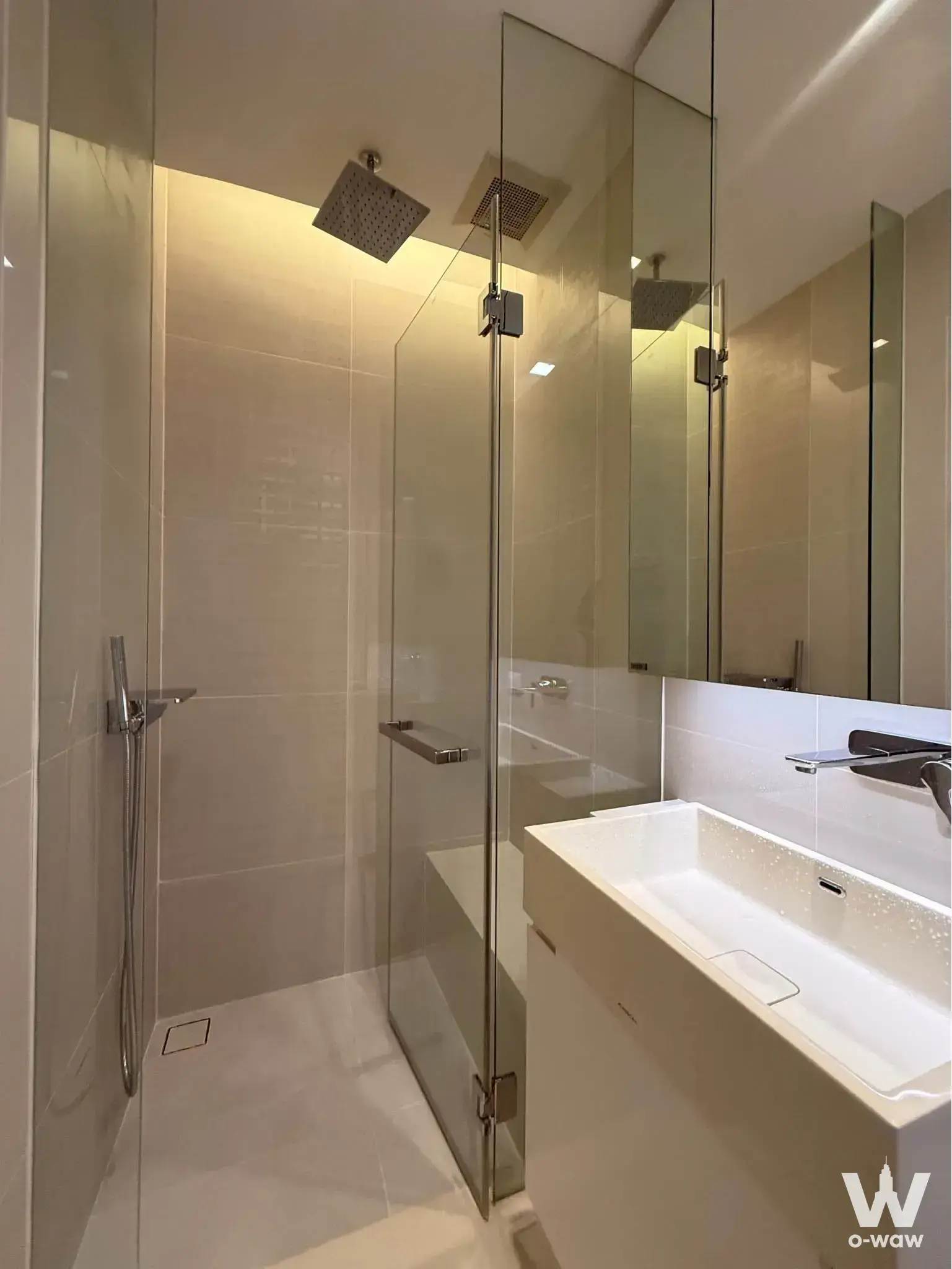 Luxury bathroom in a Bangkok condo rental with walk-in glass shower, dual rain heads, and floating vanity