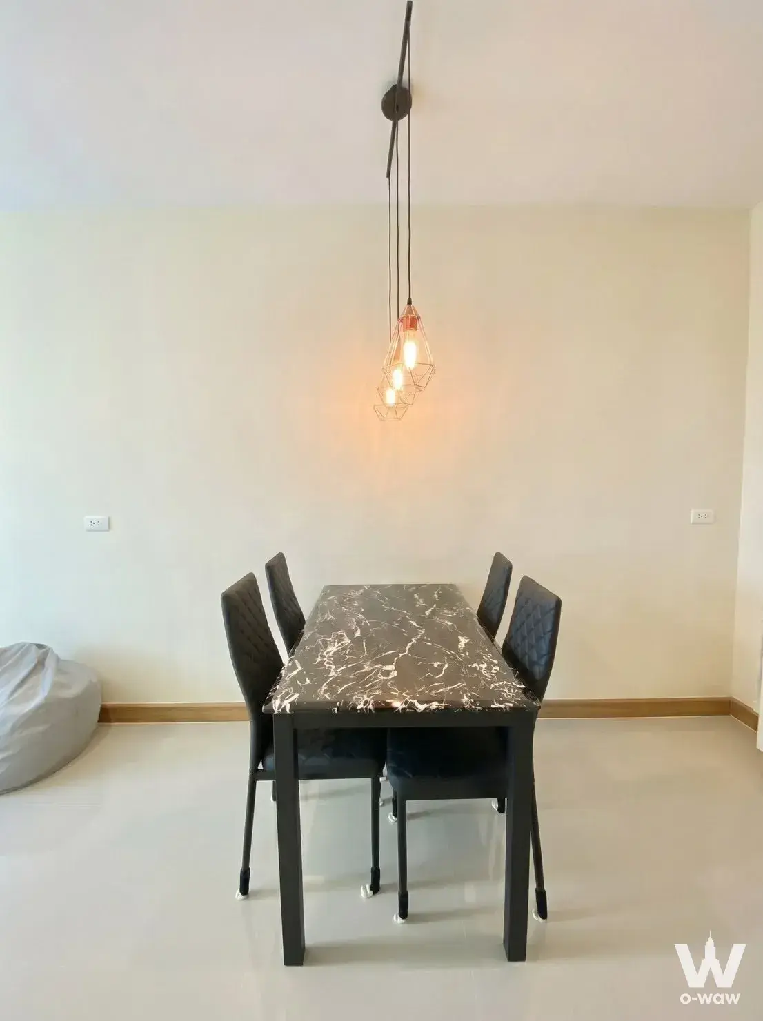 Modern minimalist dining area with black marble table and industrial pendant lights in a Golden Town 3 Bangna-Suanluang
