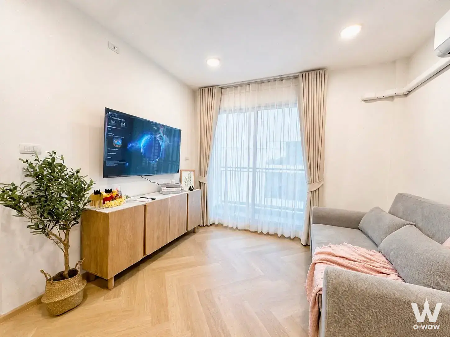 Grey sofa with pink throw and herringbone floors in this 1-bed Centric Scene Sukhumvit 64 sale listing