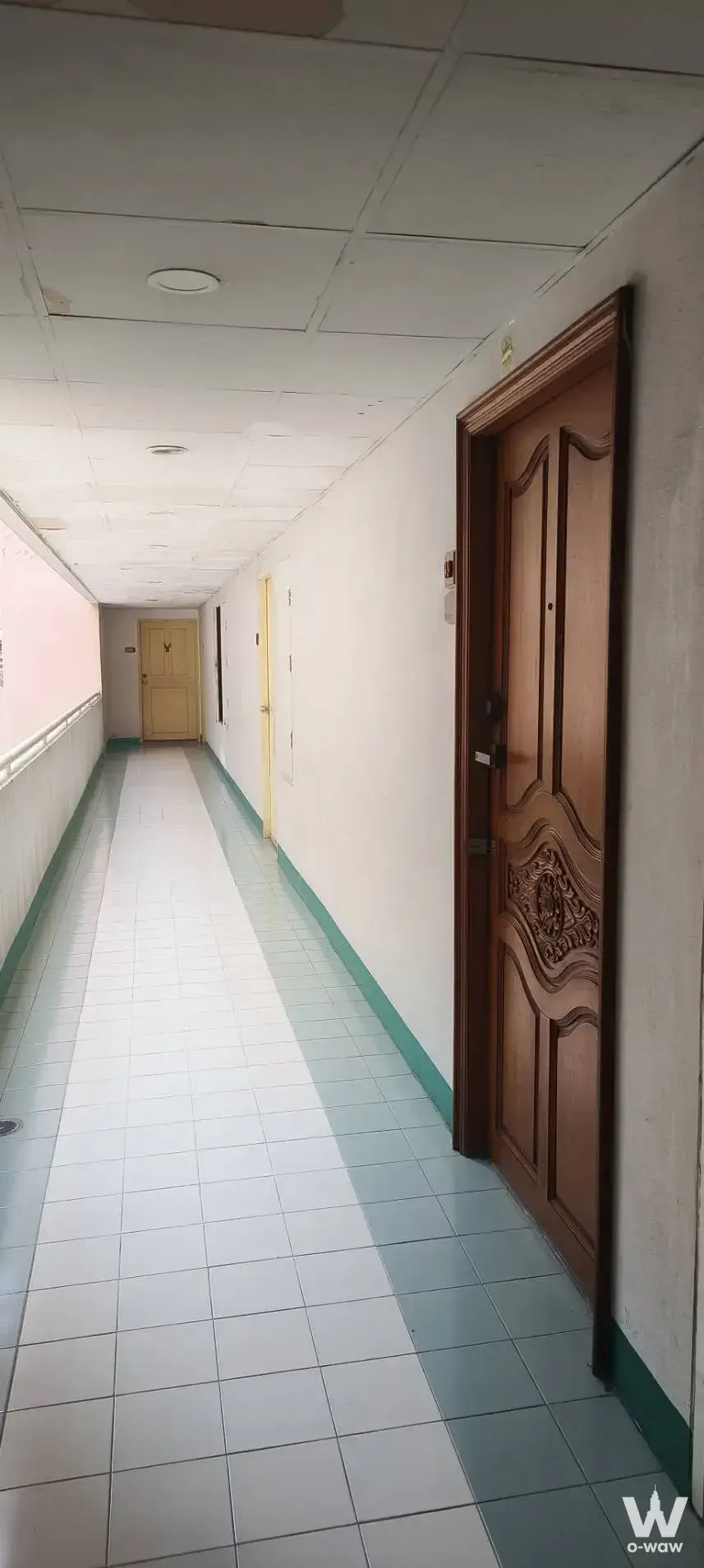 Long corridor in Tawanna Residence 2 Tower A featuring wooden doors, peeling ceiling paint, and tiled floors