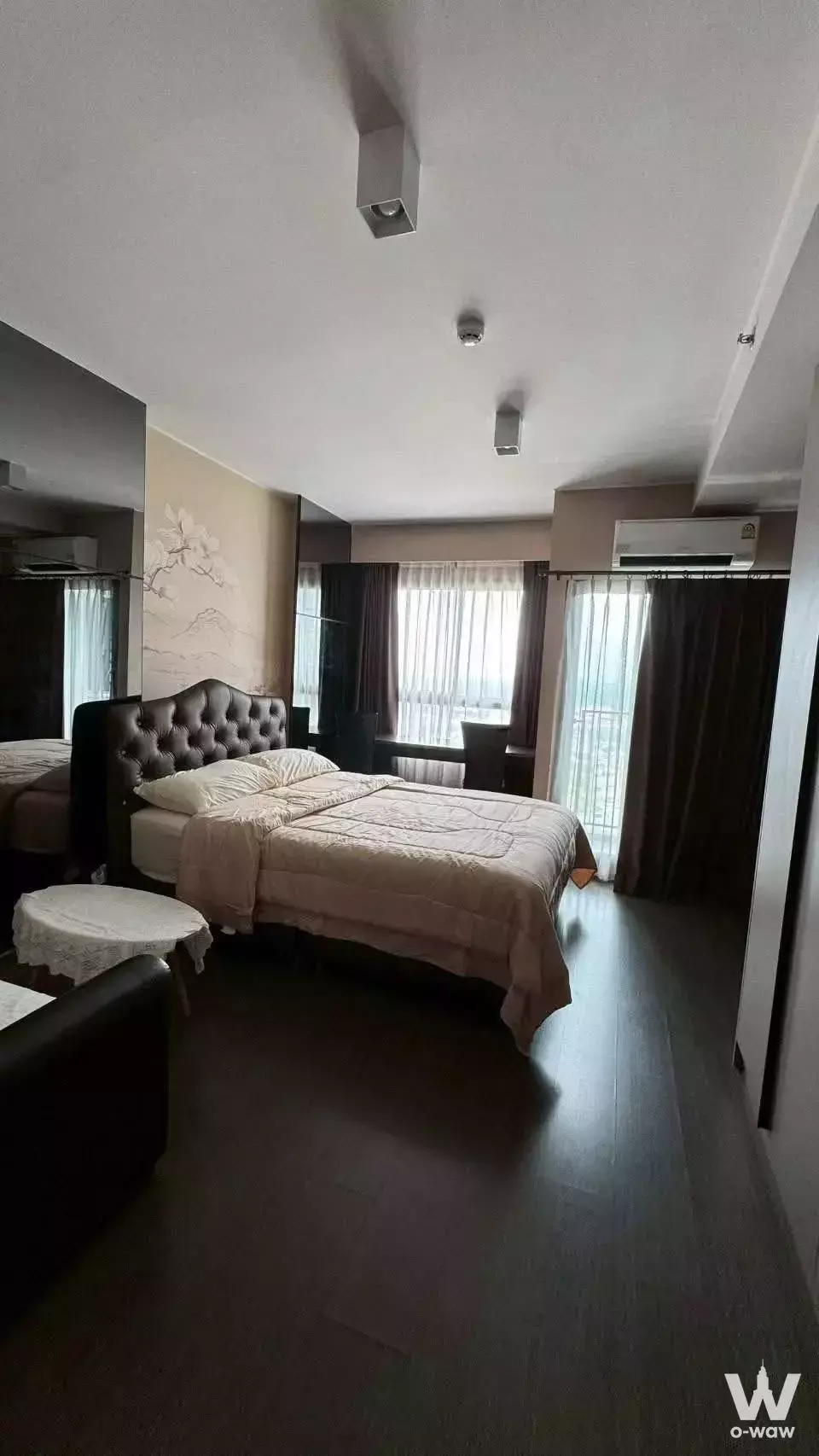 Bedroom with leather headboard and floral mural in a 1-bed condo for rent at Ideo Sukhumvit 93