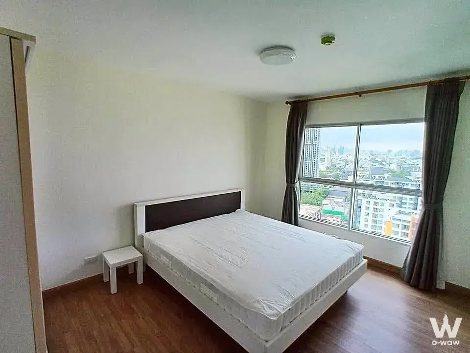 Unfurnished bedroom in S&S Sukhumvit condo featuring a queen bed and sliding glass doors with city views
