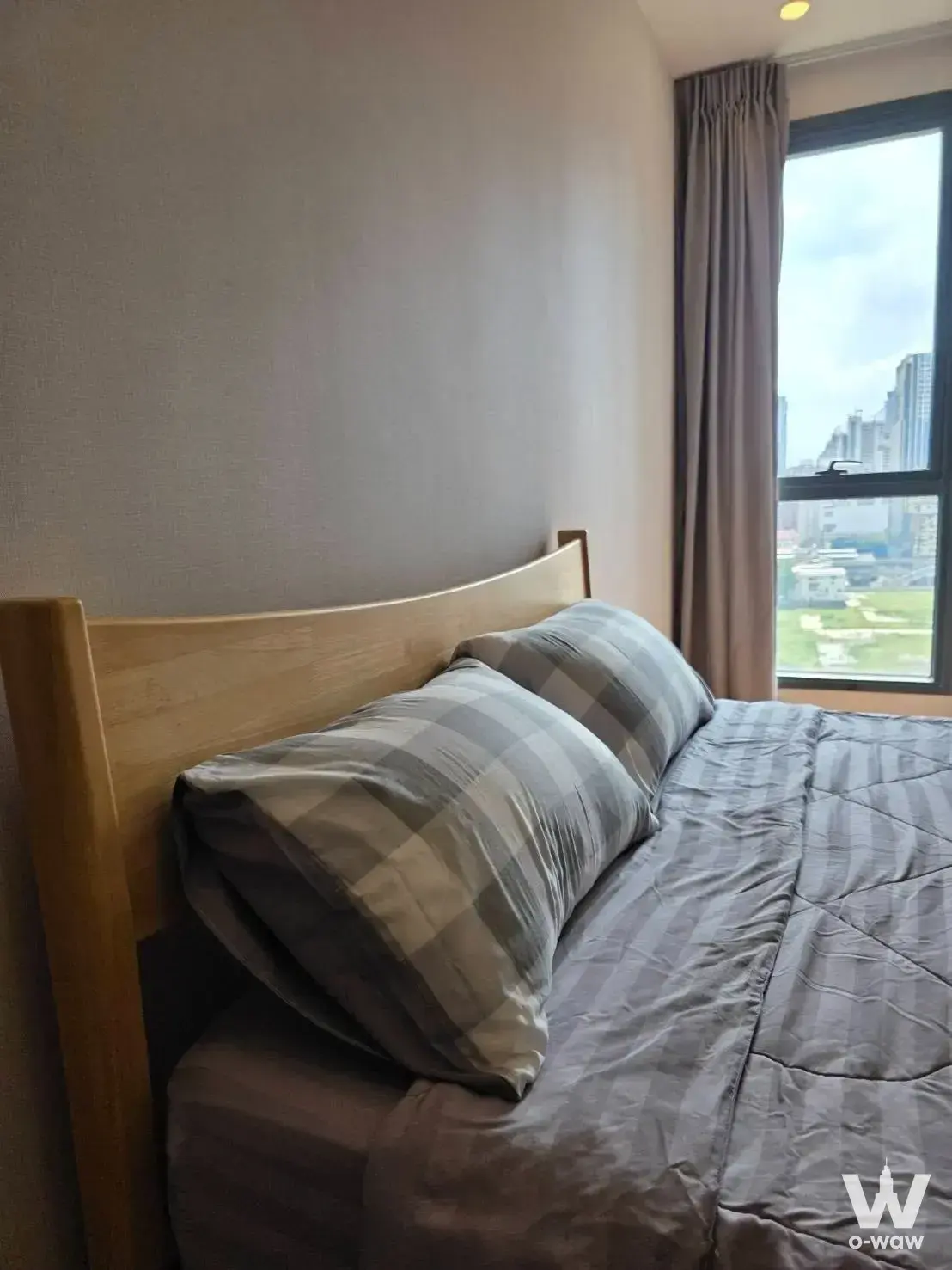 Bedroom in a Phetchaburi condo featuring a curved headboard and high-floor city view