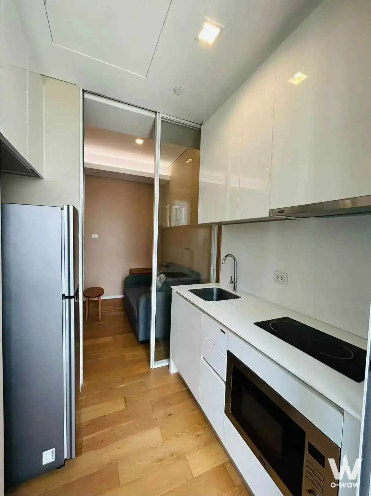 Modern 1-bed condo kitchen in The Saint Residences with white cabinetry and light oak flooring