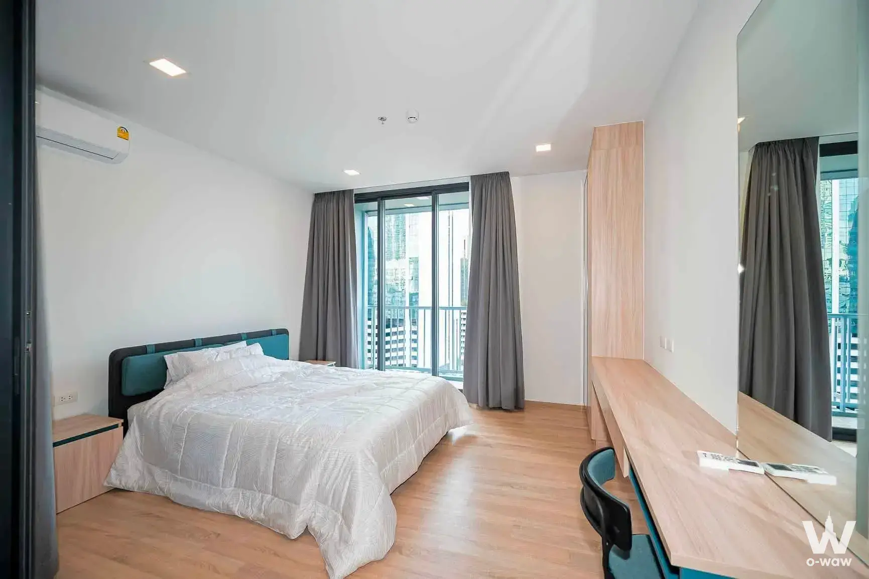 Master bedroom with teal headboard and city view in this 1-bed XT Phayathai condo for sale