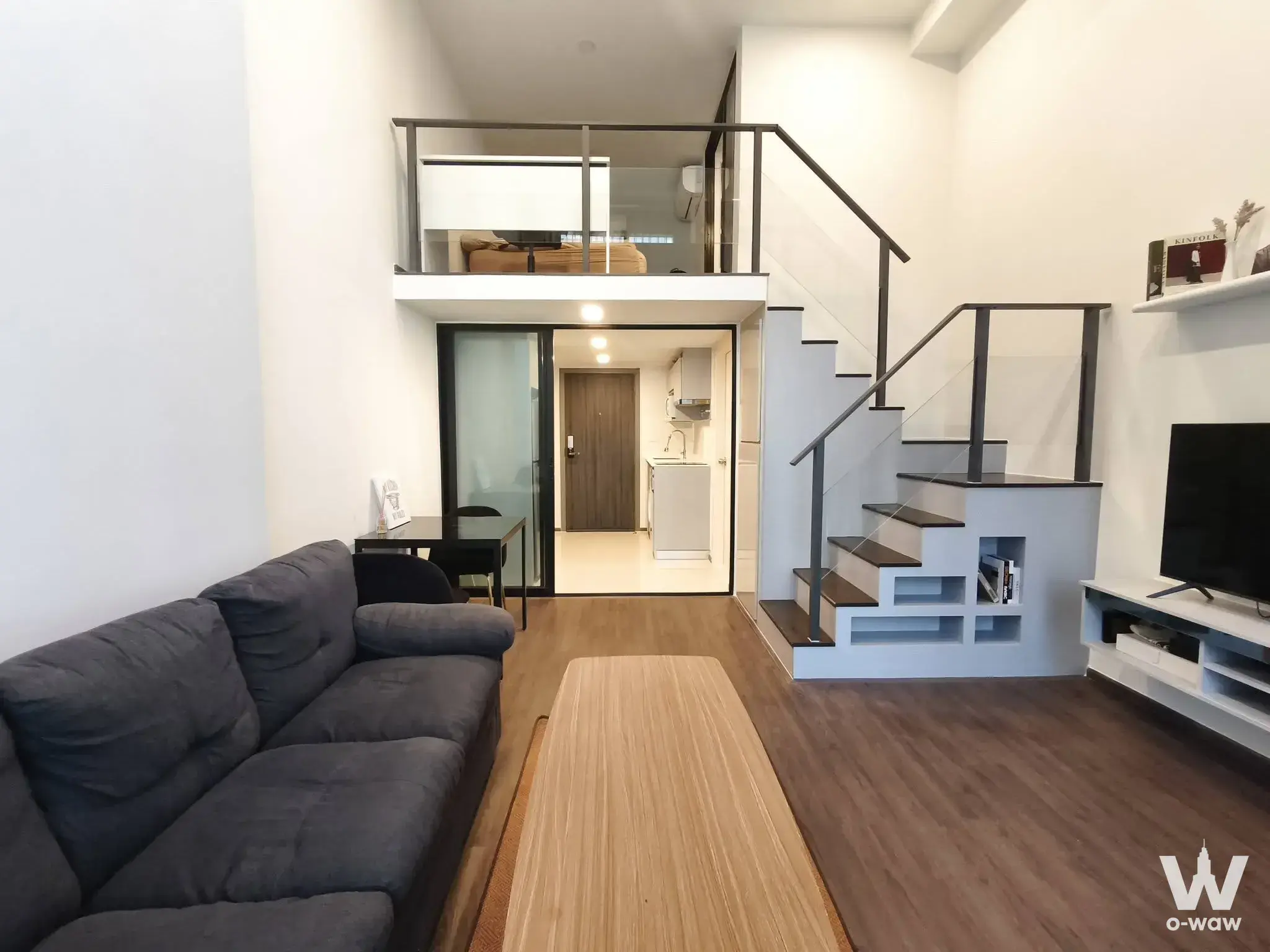 Loft-style living room in KnightsBridge Space Rama 9 with high ceilings, black staircase, and mezzanine
