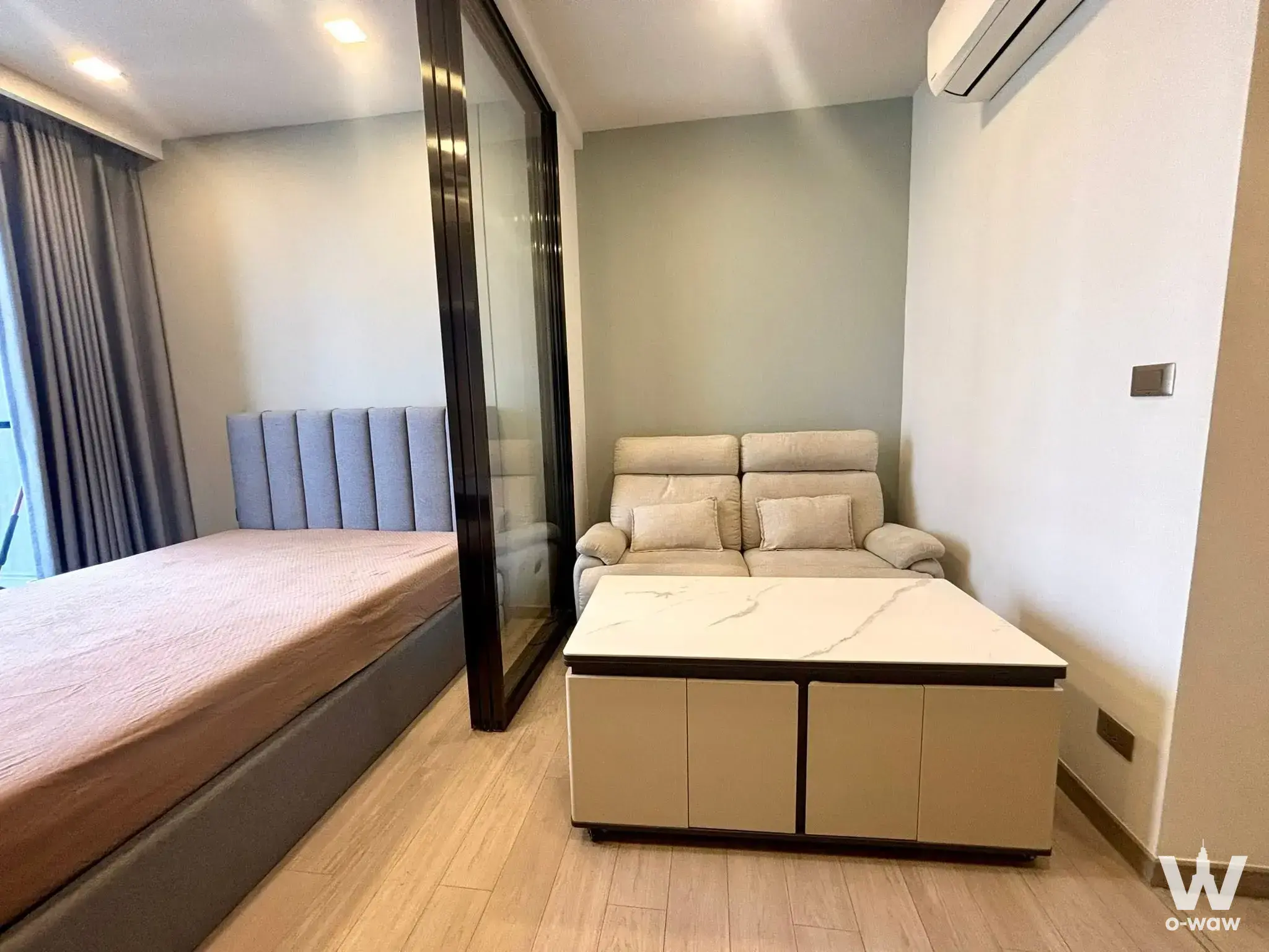 Studio bedroom in One9Five Asoke with sage accent wall, platform bed, and glass partition