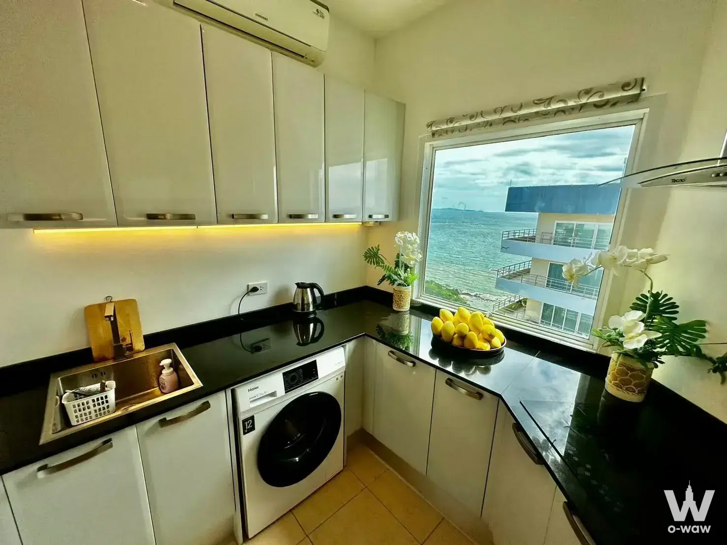 L-shaped kitchen with ocean view, glossy white cabinets, and integrated washing machine for sale at View Talay Condo 3A