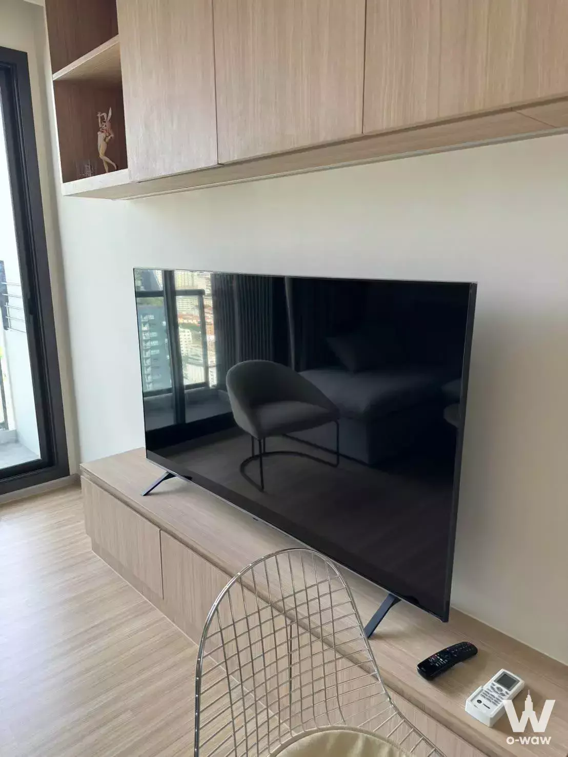 Living area in a M Jatujak 2-bed condo with floating media console and floor-to-ceiling balcony doors