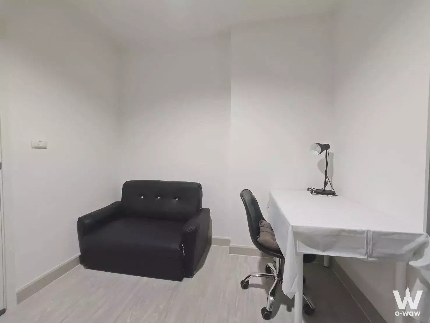 Aspire Ngamwongwan 1-bed condo rental highlighting a functional corner office setup with black leather loveseat and white