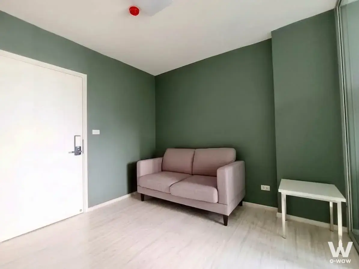 Sage-green living room in the Aspire Rattanatibet 1 rental with a dusty-pink sofa and laminate flooring