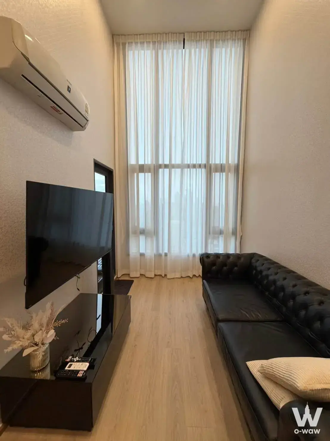 Black Chesterfield sofa facing floor-to-ceiling window in this 2-bed Life Rama 4 Asoke condo
