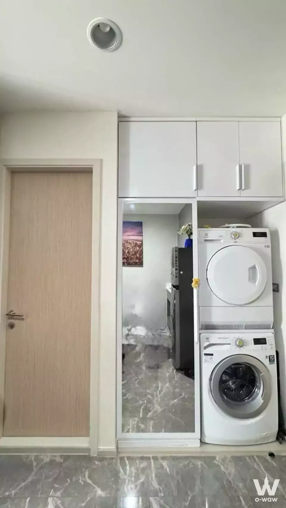 Laundry room in RHYTHM Asoke 2 with stacked washer-dryer and white built-in cabinets