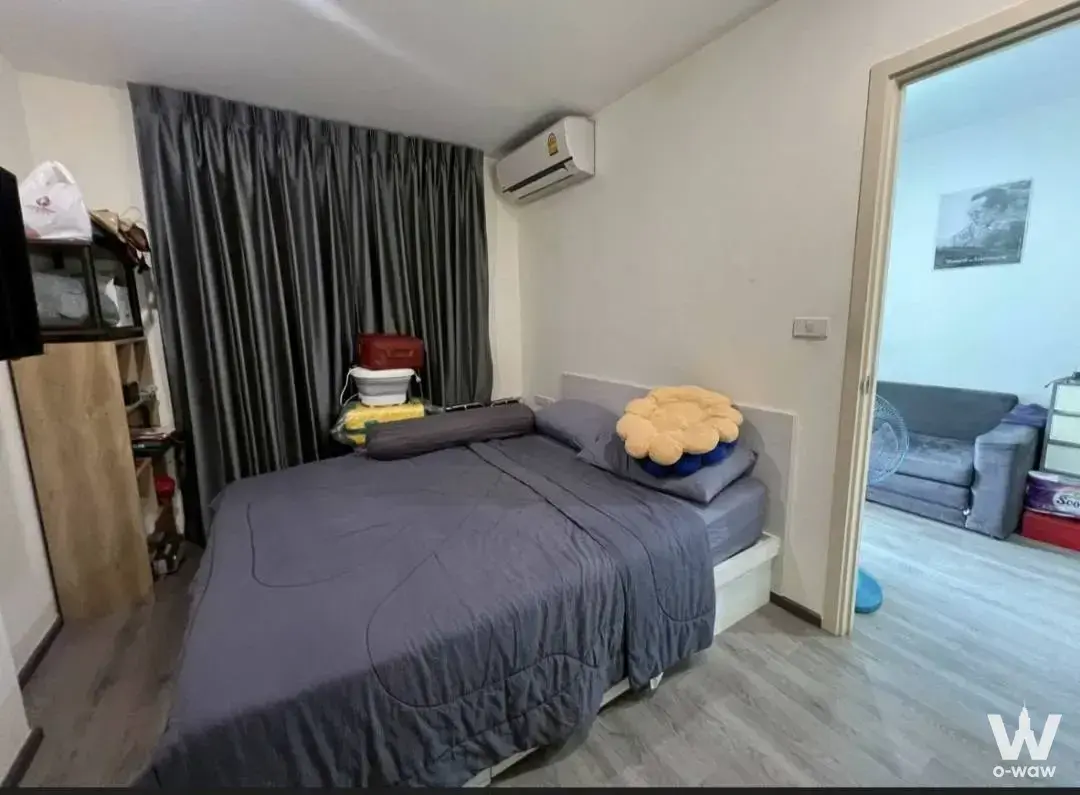 Bedroom for sale in Rich Park Triple Station condo with grey duvet, yellow accent pillow, and wooden wardrobe