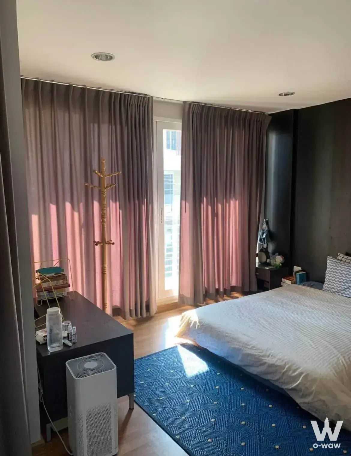 A queen bed with white textured linens and a blue geometric rug fills a 4-bed townhouse bedroom in Rama 9-Ladprao