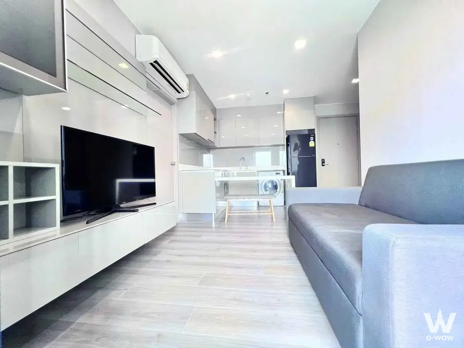 Furnished living area in a 2-bed condo for sale at The Politan Rive with white kitchenette and TV console