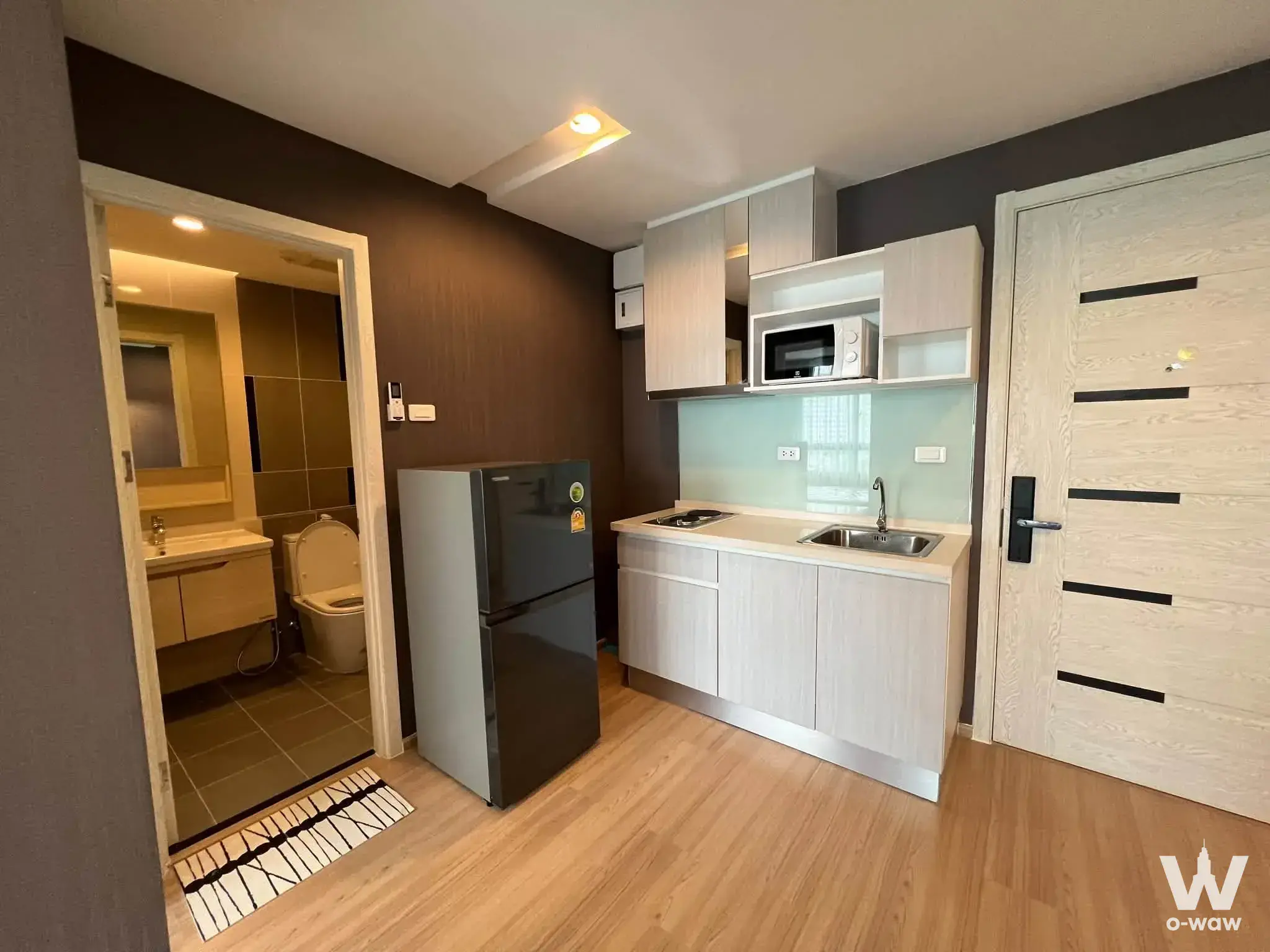 Studio kitchen in Artemis Sukhumvit 77 condo sale with mint green backsplash and light wood cabinetry