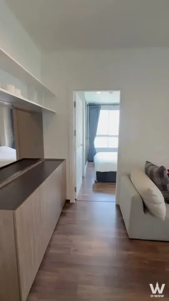 Living room in U Delight Rachavibha 2-bed sale with light wood cabinetry, cream sofa, and open view to the bedroom