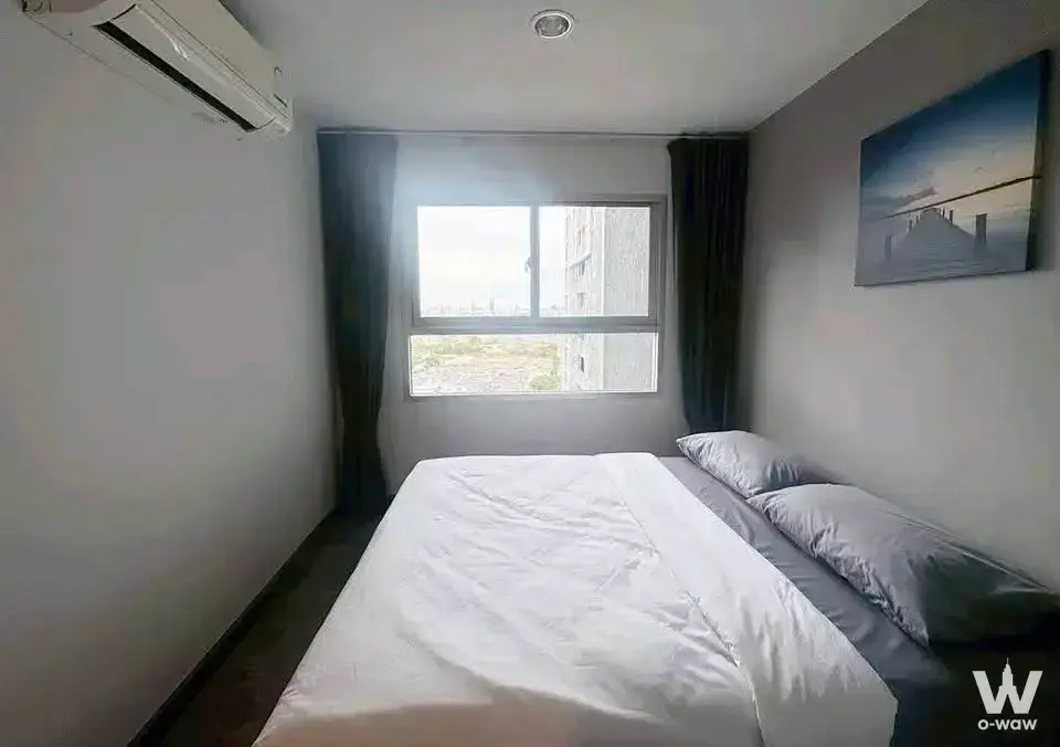 Minimalist bedroom in a 1-bed condo for rent at The Trust Condo @BTS Erawan with dark wood floors and city view