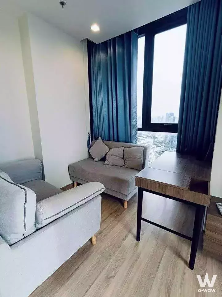 Living room in THE LINE Phahon-Pradipat with grey sofa and city skyline view