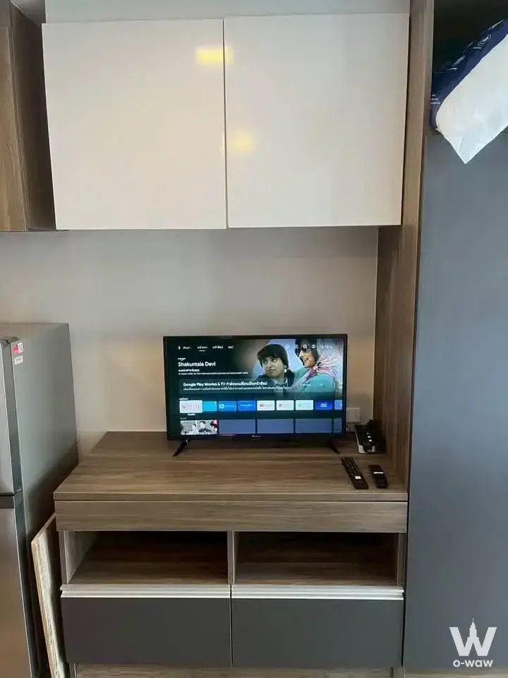 Furnished living room in a SUN CITY 1-bed condo with built-in media unit and flat-screen TV