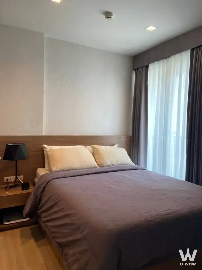 Queen bed with wood headboard in this 1-bed condo for rent at RHYTHM Sathorn