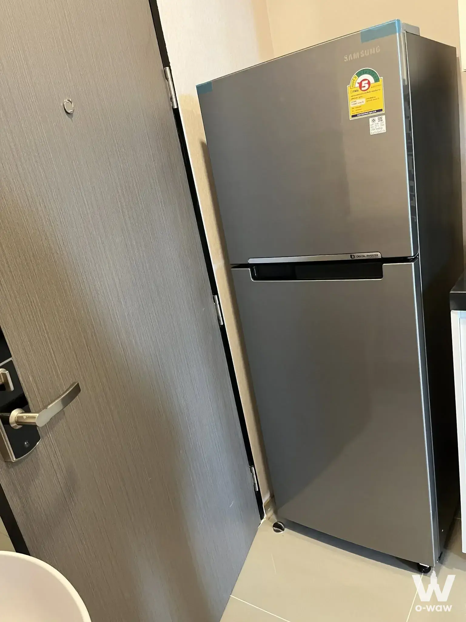 Compact kitchen corner in a Bangkok condo featuring a stainless steel Samsung fridge and grey wood-grain door