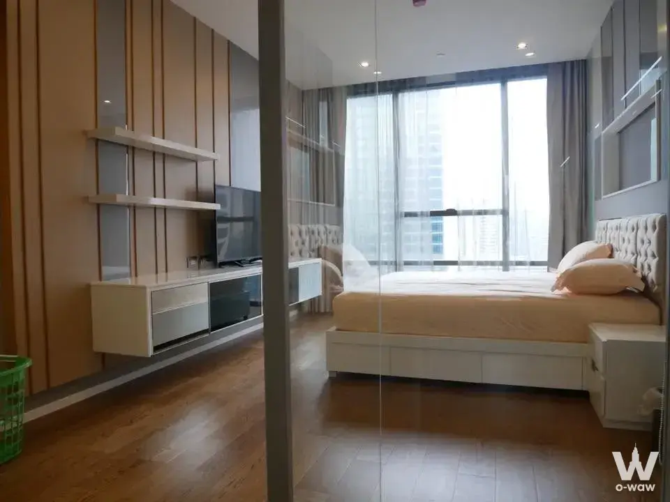 Bedroom in The Bangkok Sathorn condo with a queen bed and floor-to-ceiling windows overlooking the city