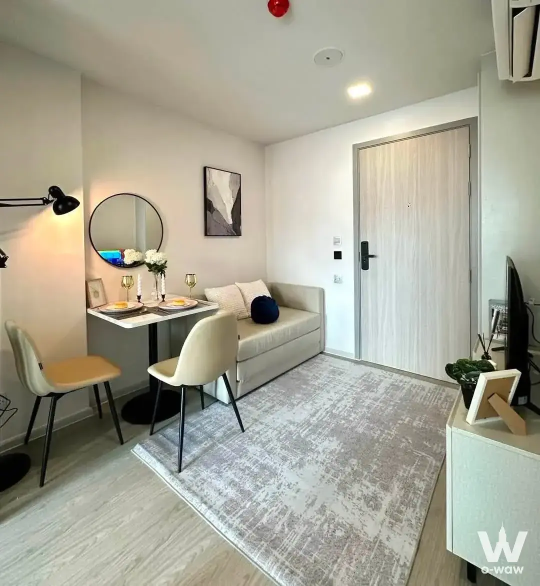 Furnished studio living space in Atmoz Oasis Onnut featuring a cream sofa bed, marble dining table, and minimalist decor