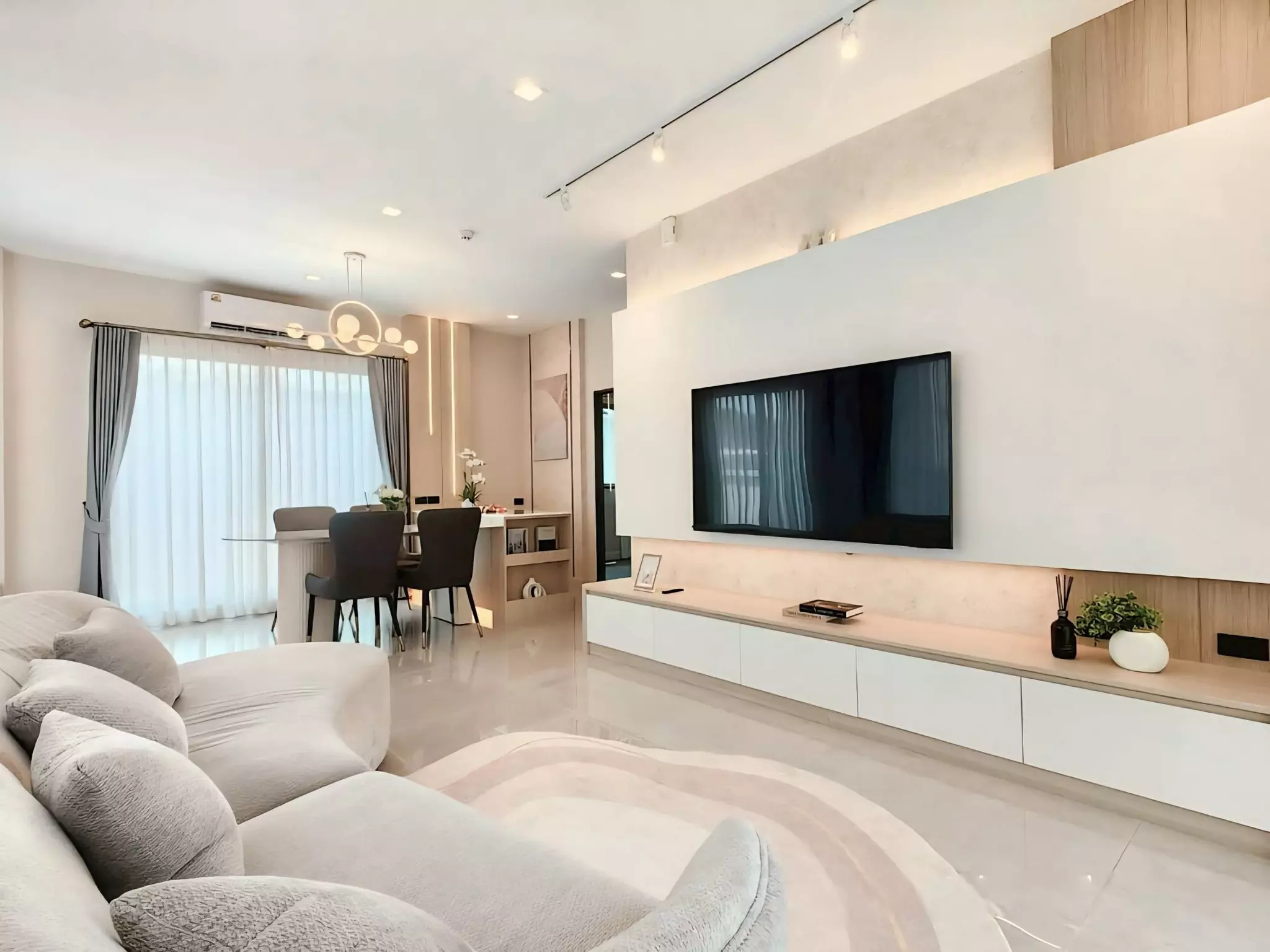 Open-plan living area in a Bangkok Boulevard Bangna KM.5 home featuring a curved sectional sofa and warm LED accent lighting