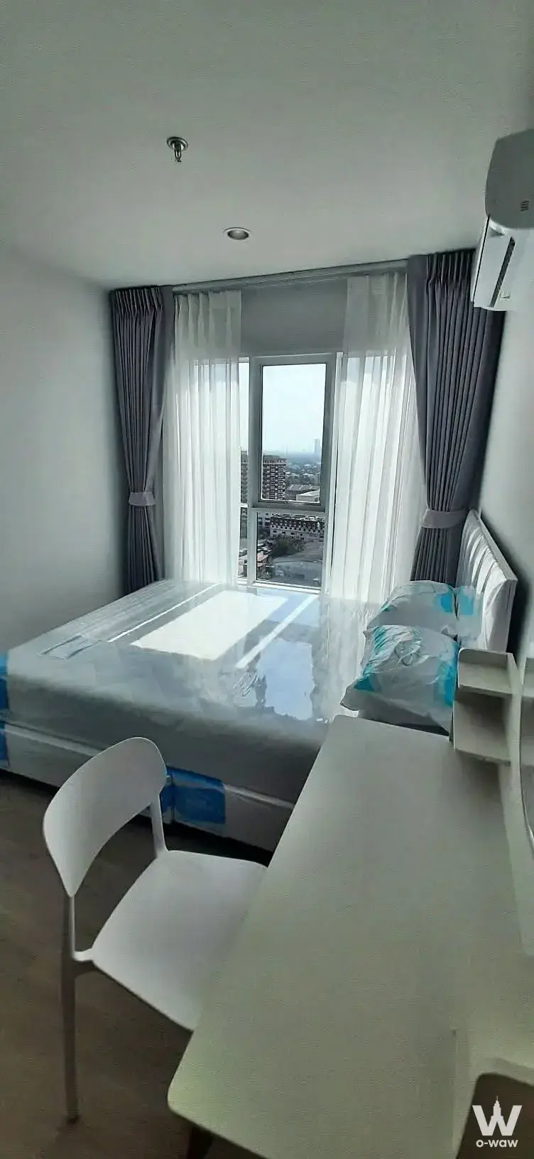 Newly renovated bedroom featuring a plastic-wrapped queen bed and desk in Regent Home Bangna