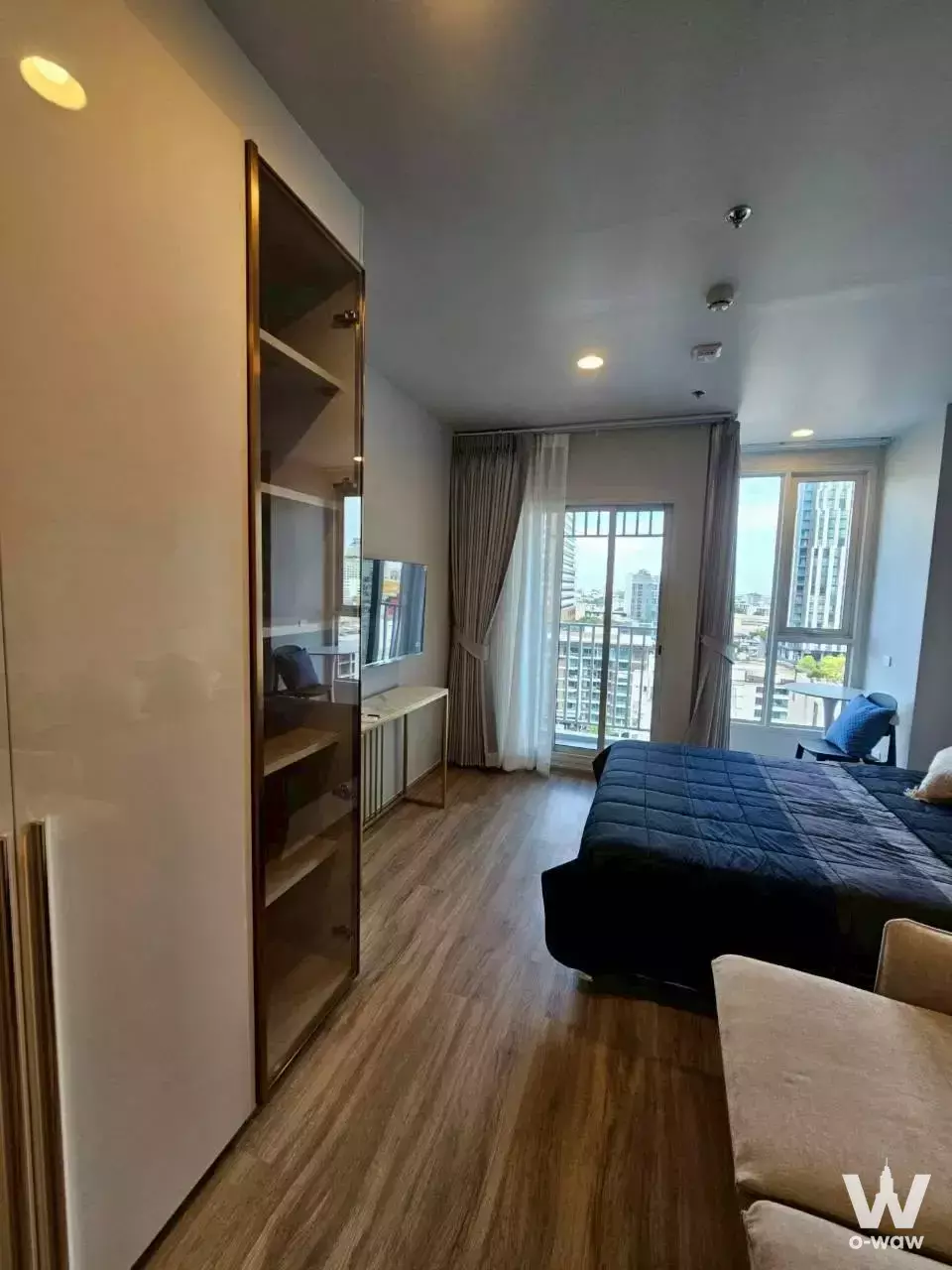 Modern bedroom in Culture Thonglor condo featuring navy duvet, brass-handled wardrobe, and city views from high floor