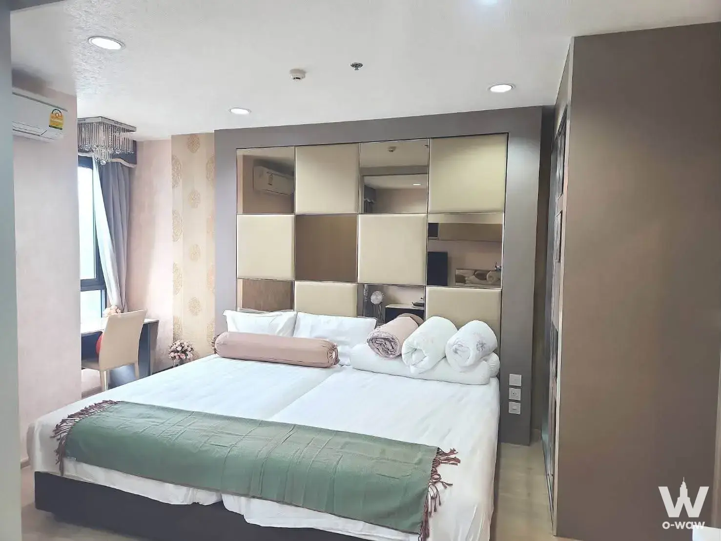 Bedroom in an Ideo Q Ratchathewi unit featuring a king bed and mirrored grid accent wall