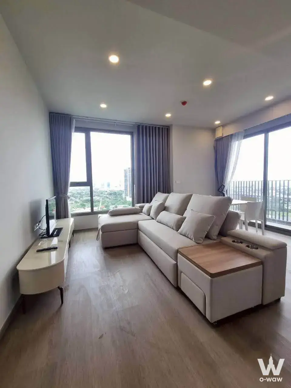 Living room in a Whizdom The Forestias condo with a beige sectional sofa and floor-to-ceiling windows