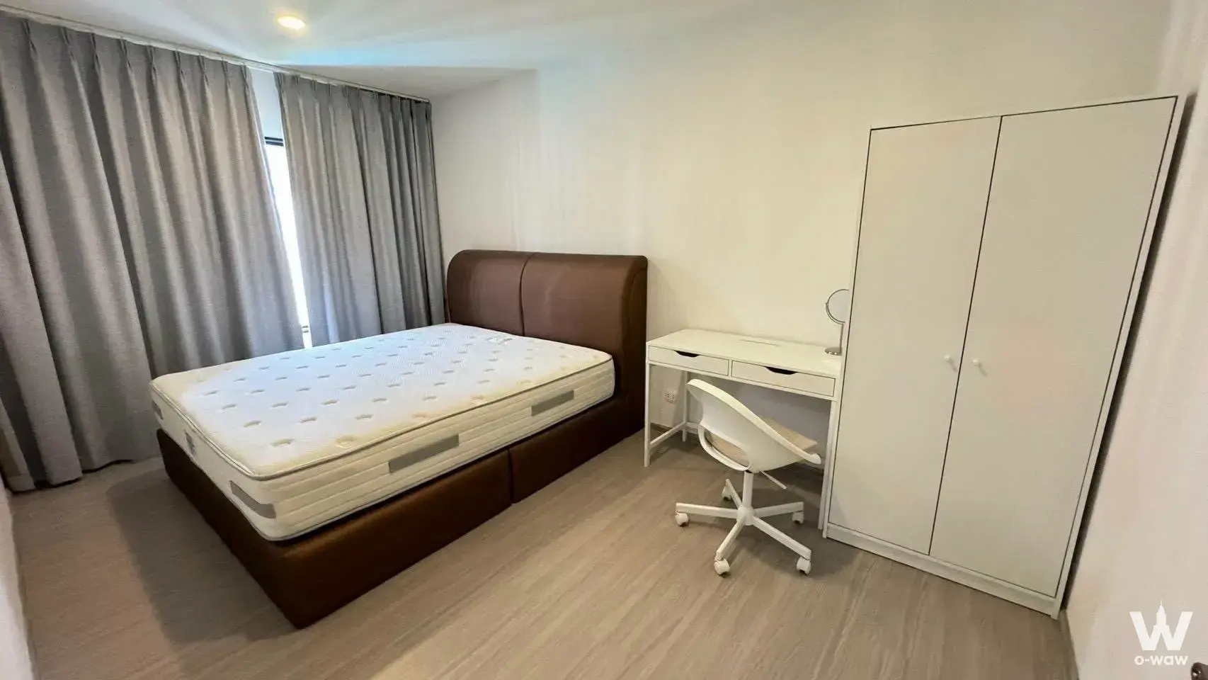 Bedroom with dark leather headboard and desk in Aspire Sukhumvit-On Nut 2-bed condo
