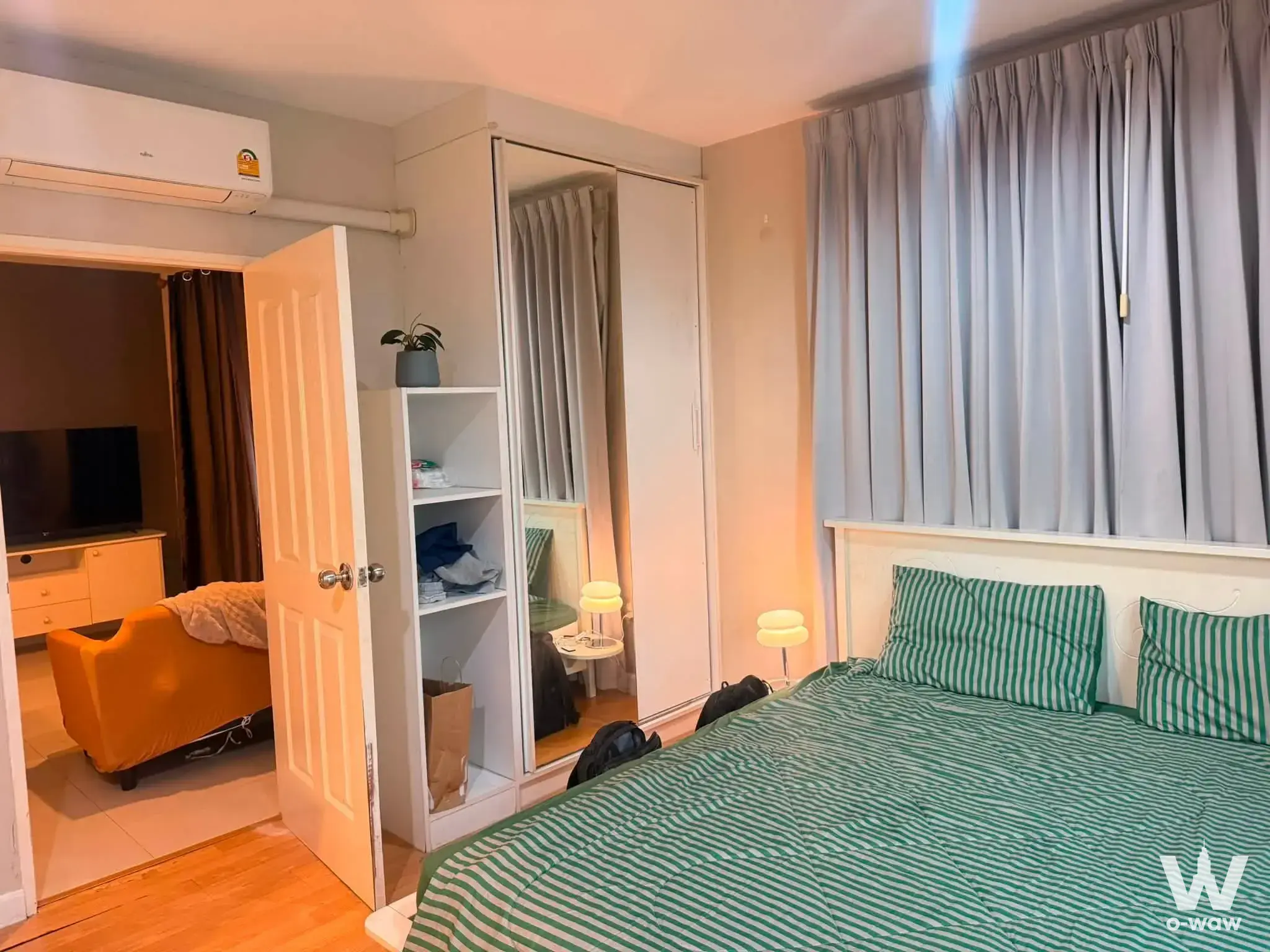 Modern bedroom with green striped duvet and mirrored wardrobe in City Home Sukhumvit 1-bed rental