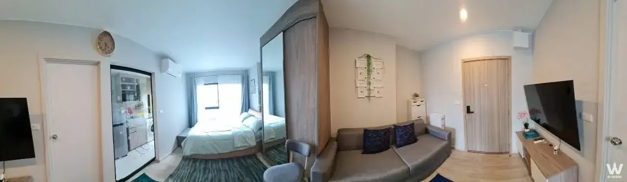 Furnished studio in Plum Condo Sukhumvit 97.1 with light wood floors, grey sofa, and compact kitchenette