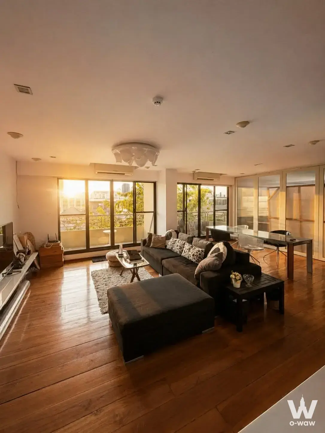 Sunlit open-plan living and dining area in a 2-bed condo for rent at Supreem Will, with charcoal sectional and balcony view
